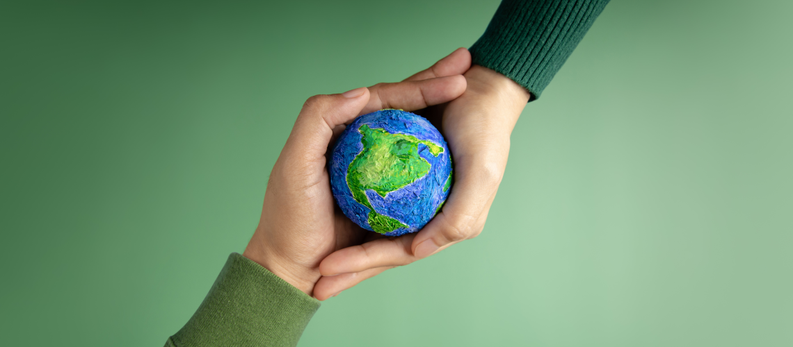 Zdjęcie poglądowe: Ziemia w troskliwym objęciu dłoni, na zielonym tle. Teoria pięciu przemian - Element ziemi – wzmocnij swoje centrum i poczucie bezpieczeństwa?