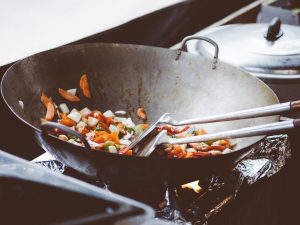 Kuchnia Pięciu Przemian – warzywa w woku na ogniu – przepisy dietetyki TCM Warzywa w stalowym woku na otwartym ogniu – marchew, cebula i papryka, gotowane według zasad Kuchni Pięciu Przemian.